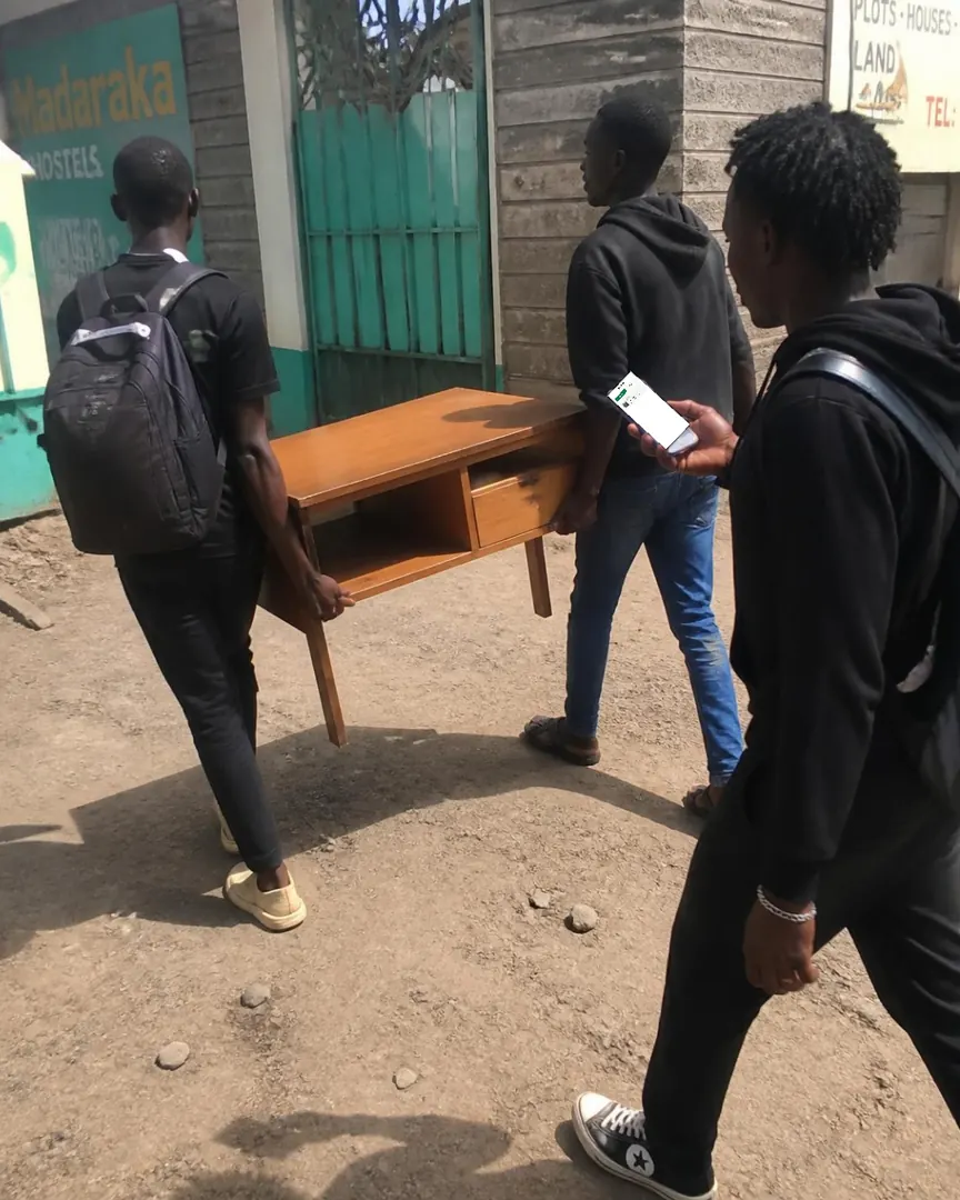 Students carry a study desk out of a hostel while one checks the claim in Chukua